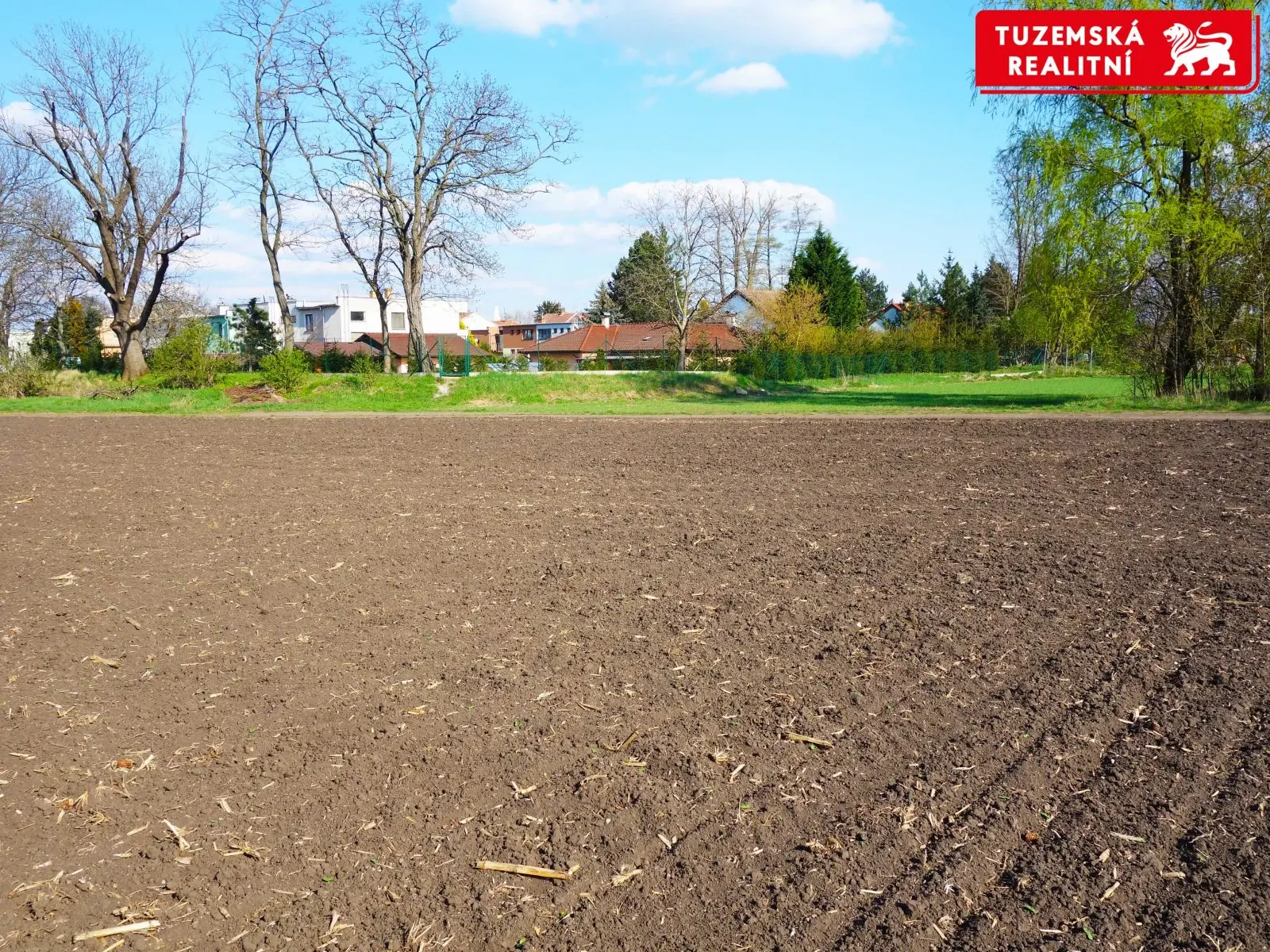 Hned u zástavby rodinných domů zemědělský rovinatý pozemek.